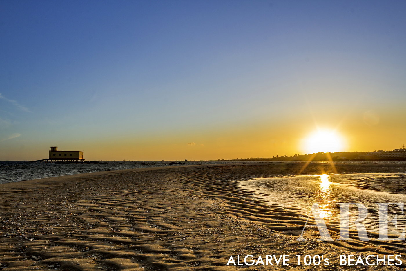 Atardecer en Fuseta. La Antiga Estação Salva-Vidas da Fuseta, un edificio histórico, se alza con orgullo en el lado izquierdo del marco, su silueta crea un sorprendente contraste con el colorido cielo.