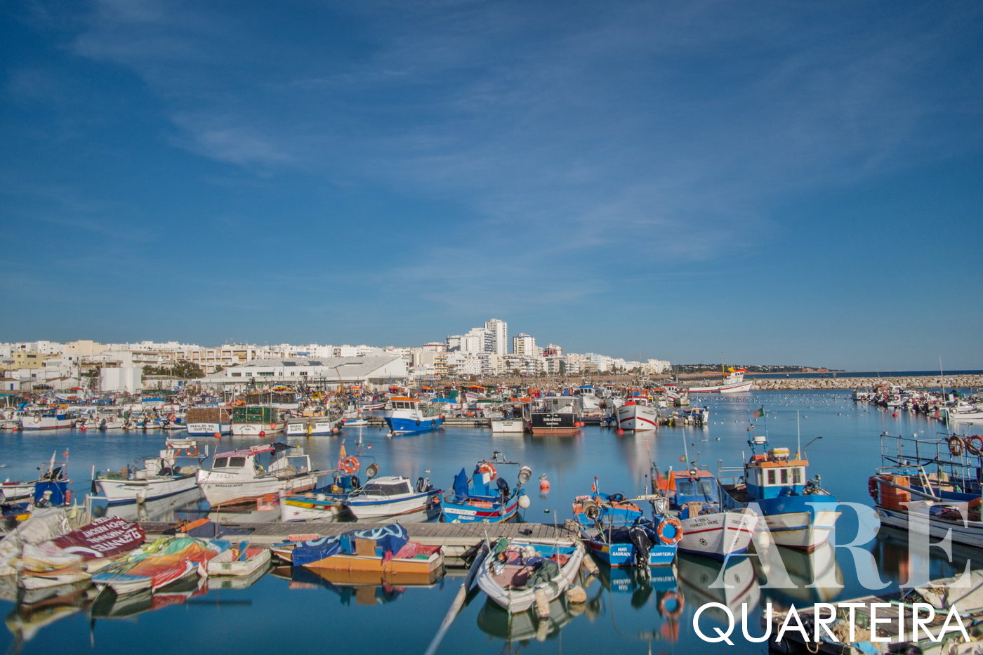 Barcos pesqueros en el puerto de Quarteira, horizonte de la ciudad al fondo