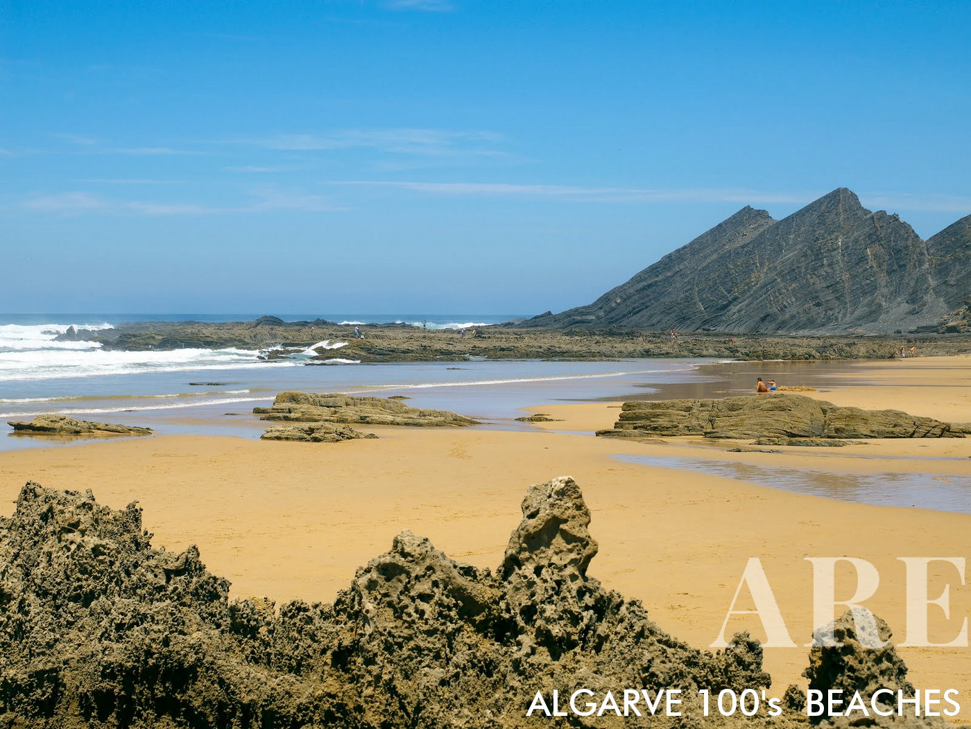 En la playa de Amoreira en Algarve, Portugal, espectaculares acantilados rocosos marchan hacia el océano, su grandeza reflejada en intrigantes formaciones rocosas reveladas en la orilla arenosa durante la marea baja.