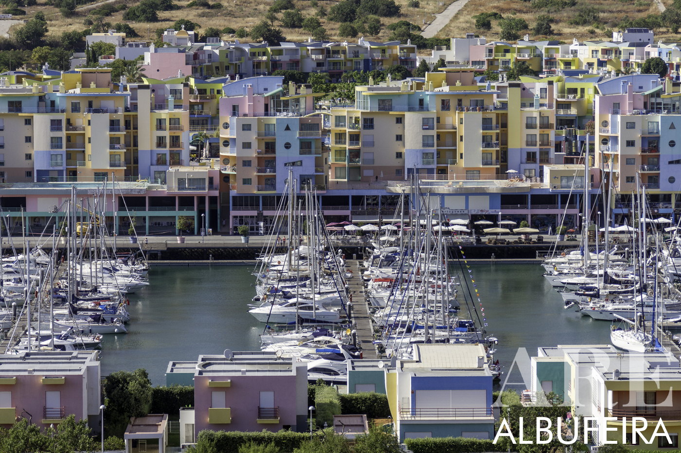 Albufeira Marina, featuring the distinctive yellow, blue, pink, and orange buildings designed by renowned architect Taveira. Serving as the departure point for tours to the Benagil cave, dolphin watching, and diving, it's home to the famed Zen Mar boat trips operated by Marco and Anne. The marina is also adorned with restaurants, making it a prime spot for relaxation and culinary delights.