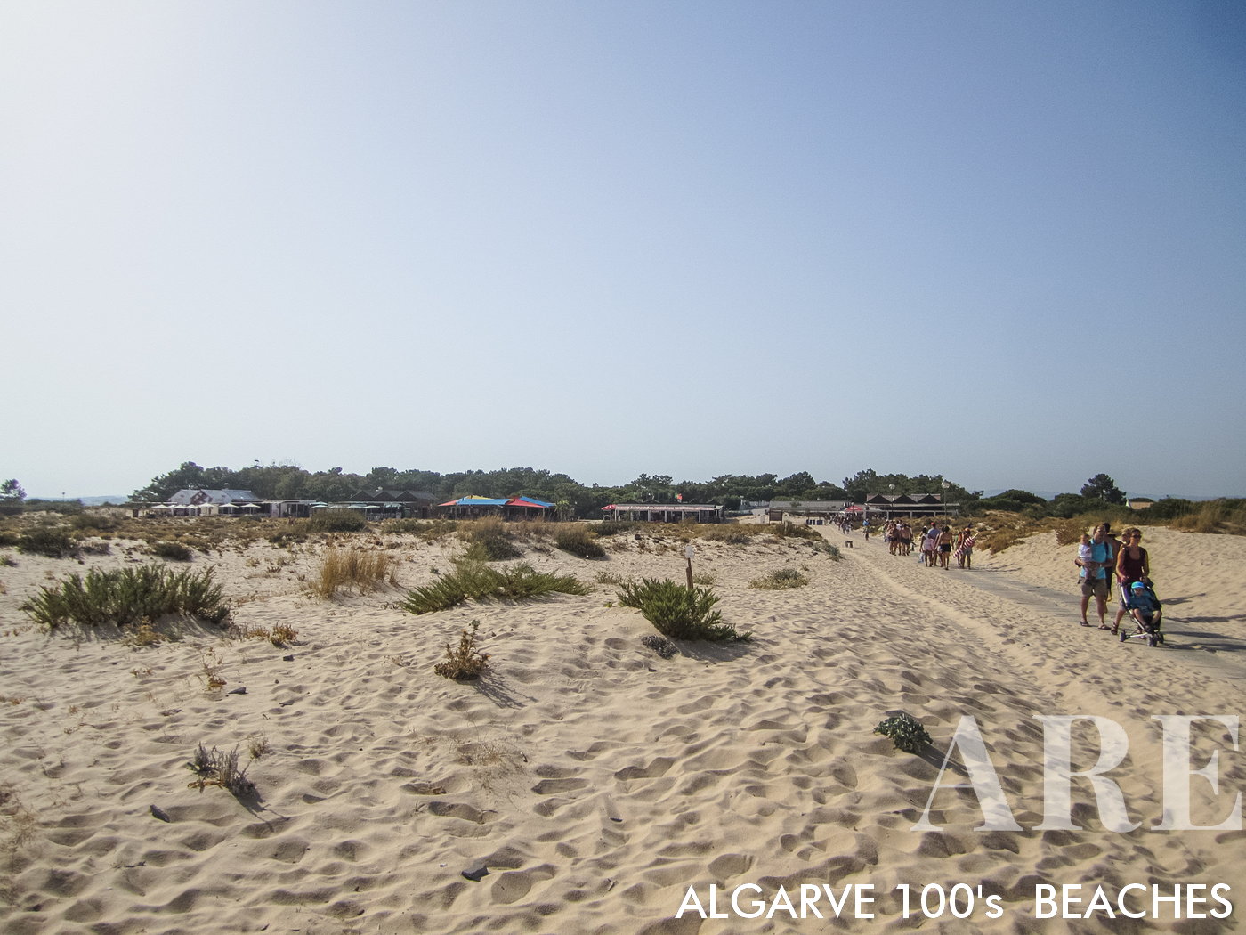 Playa de la isla de Tavira, un paraíso de arena prístino y extenso ubicado en el Algarve, Portugal. Accesible solo por barco, esta larga extensión de arena ofrece un escape tranquilo para los bañistas. Deléitese con las ofertas de los restaurantes junto a la playa y tome el sol en las cómodas tumbonas. En el lado oeste de la playa, abraza la libertad del naturismo.