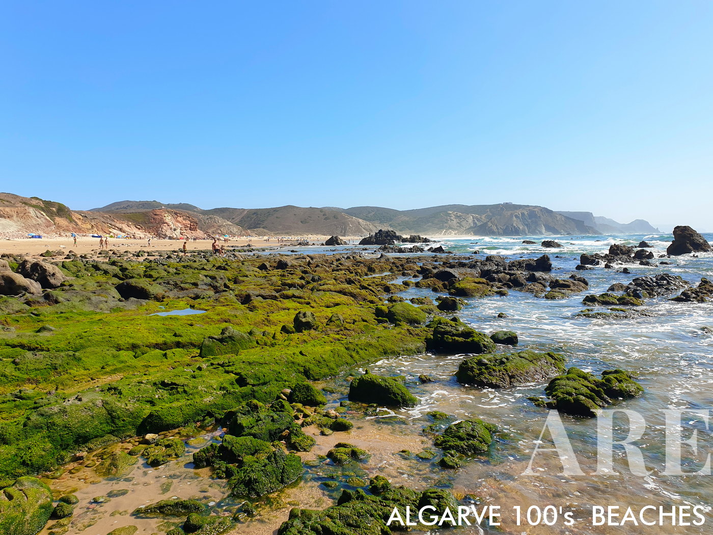 Do lado norte da Praia do Amado na maré baixa, a vista de rochas verdes expostas e pequenas piscinas naturais oferece uma perspectiva única sobre a beleza sempre em mutação desta praia.