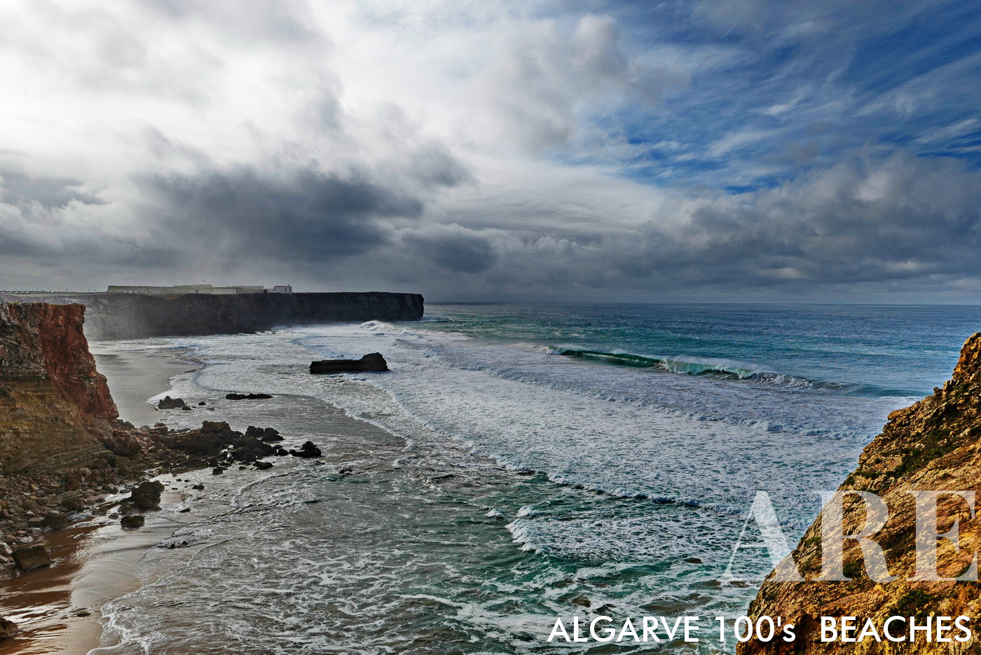 A tempestade de inverno pinta uma cena dramática na Praia do Tonel, com ondas turbulentas quebrando sob um céu sombrio, e a estóica Fortaleza de Sagres em vigília em primeiro plano.