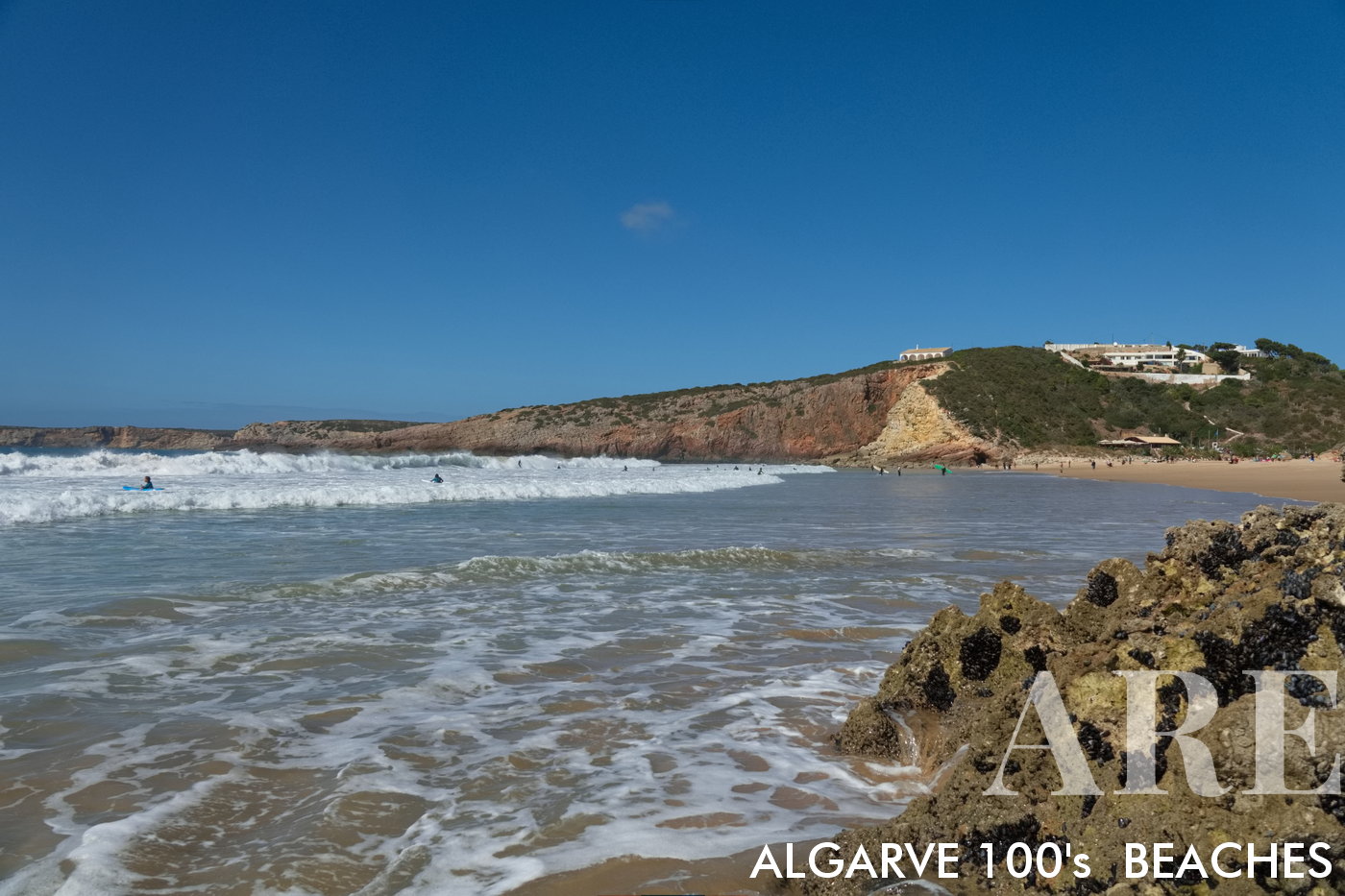 Com os pés na água na Praia do Zavial, uma vista arrebatadora se estende de leste a oeste, revelando a extensa linha costeira em toda a sua glória natural.